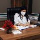 Dr. Iram seated in her office, wearing a mask and white coat, while reviewing patient documents.